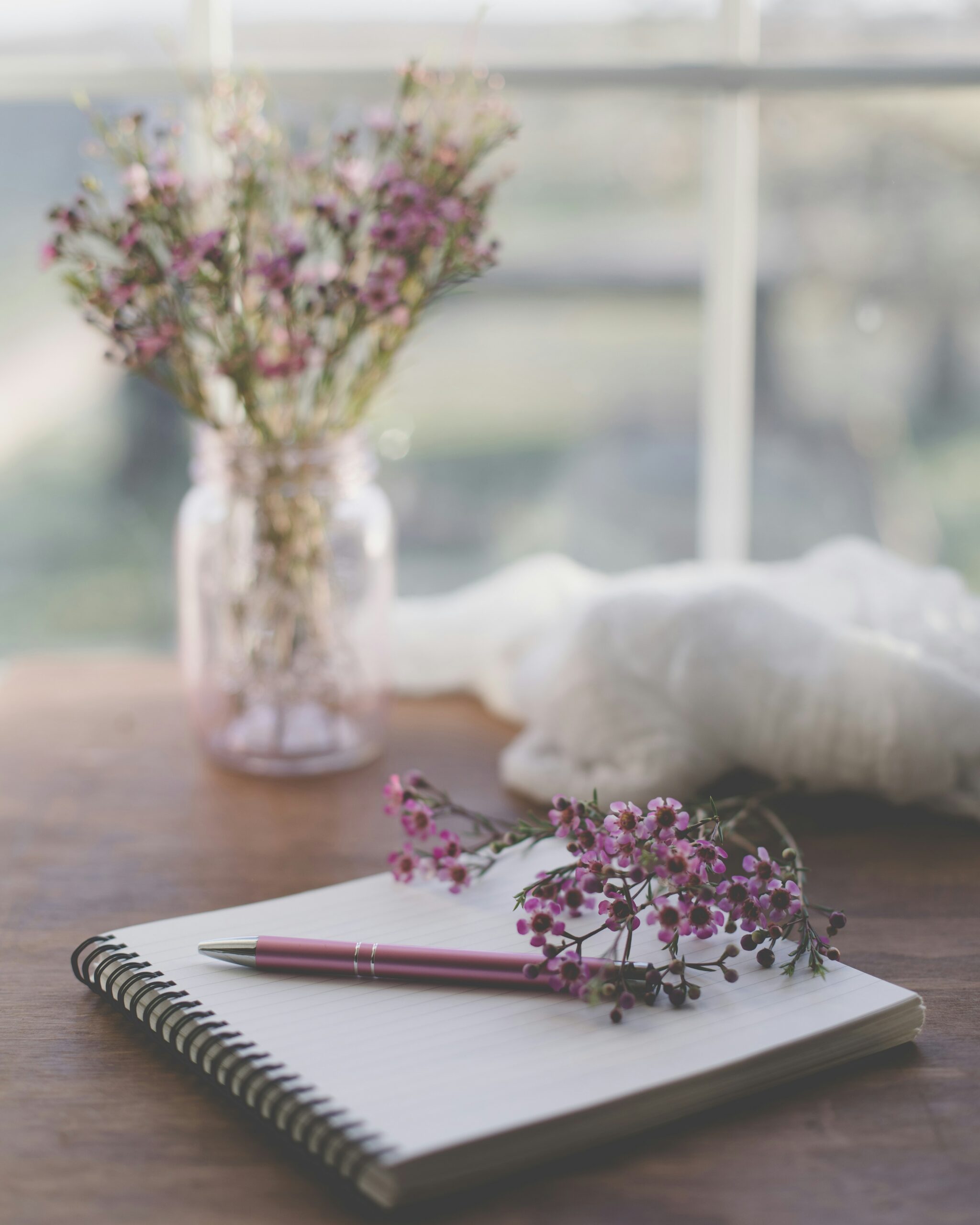 Positive Psychologie Übungen: Tagebuch und Stift auf einem Tisch am Fenster